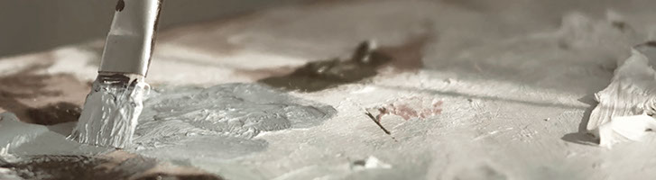 close-up photo of a paintbrush mixing paint on a wooden palette