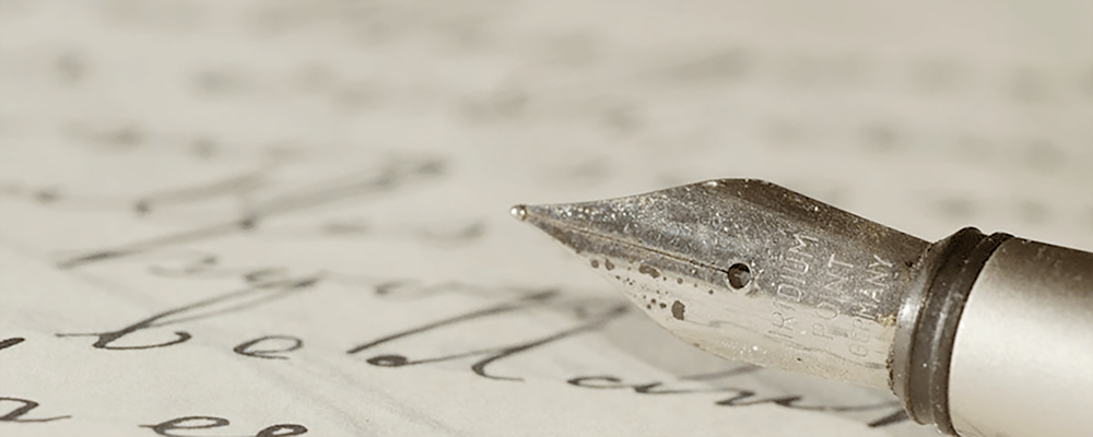 close-up photo of an ink pen with handwriting on a sheet of paper 